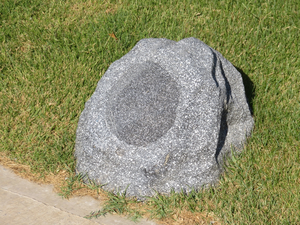 outdoor-speaker-shaped-like-granite-boulder-on-green-grassy-lawn