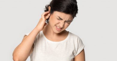 Young woman holding her right ear in pain and grimacing.