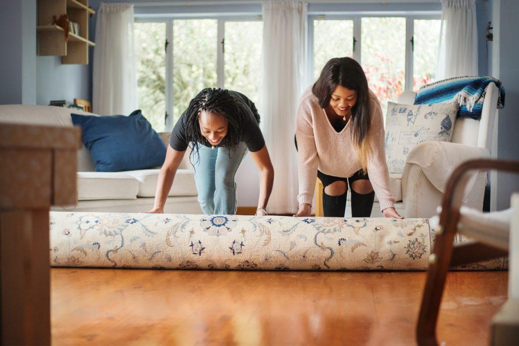 Two women adding their signature touch to a room with a new rug.