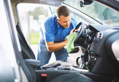 Man cleaning his car's interior using a cloth and a car cleaning gel.
