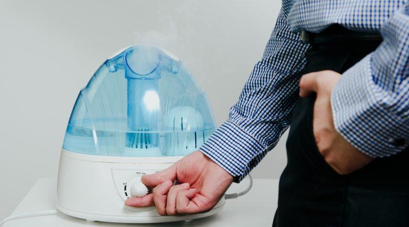Man turning on his AquaOasis Cool Mist Humidifier which helps relieve his seasonal allergies.