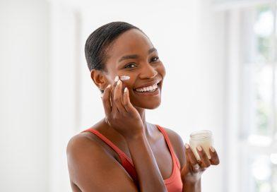 Smiling young woman applying moisturizer on her face - using COSRX Korean Skin Care set.