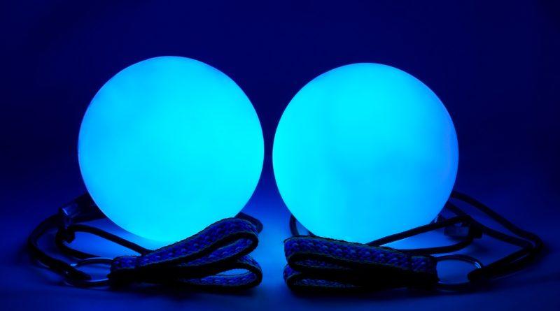 LED Poi balls emitting blue light in the dark - placed on top of a table.