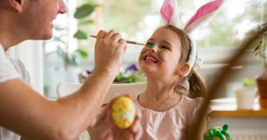 Father and daughter decorating Easter eggs using paint and an egg decorator kit.