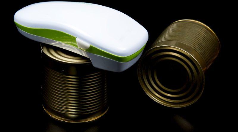 An electric can opener on top of a canned good.