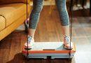 Woman at home using the PowerFit Elite Vibration Plate with its resistance bands.