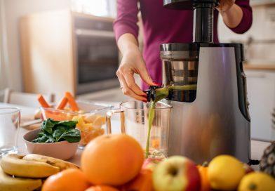 Woman preparing healthy juices made from fruits and vegetables using a smart home juicer.