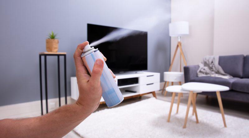 Hand spraying air freshener at home - using air fresheners to eliminate odor.