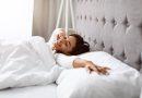 Woman waking up from a good sleep - using bamboo sheet set for her bed.