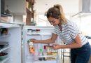 Using GE Double-Door Compact Refrigerator - Woman filling up her grocery list while checking her fridge.