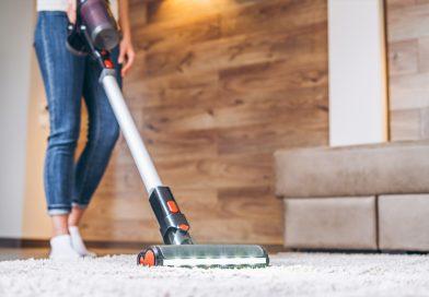 Using a cordless vacuum to clean - woman cleaning her home's carpet.