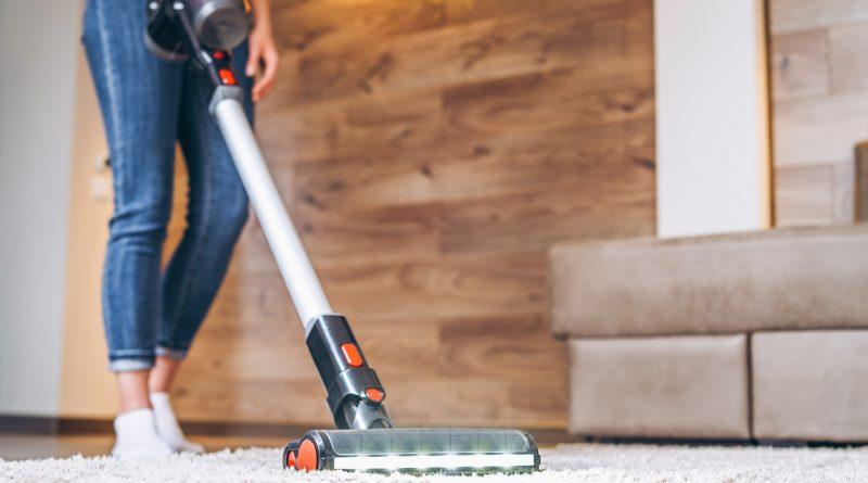 Using a cordless vacuum to clean - woman cleaning her home's carpet.