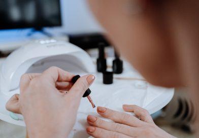 Gel nail polish kit - Woman painting her nails using gel nail polish and UV lamp.